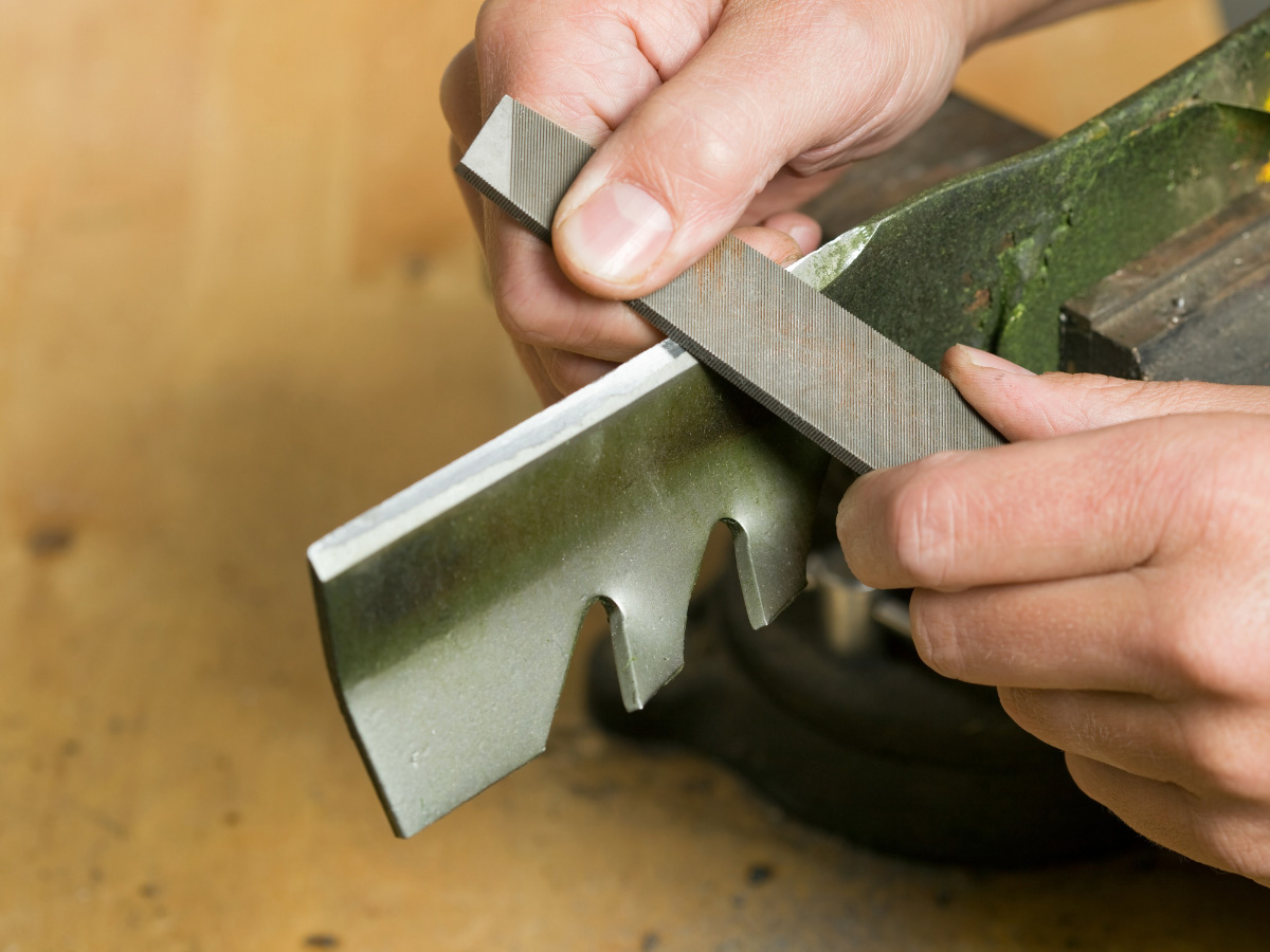 Close up of a lawn mower blade being sharpened for spring maintenance